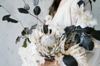 a modern black and white wedding bouquet with white blooms, black foliage and dried grasses plus a king protea is unique