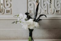 a modern wedding bouquet of white roses and orchids, black callas and blooming branches is ultimately edgy