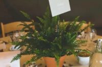 a potted fern with a name of the table is a cute and fresh wedding centerpiece for a woodland celebration