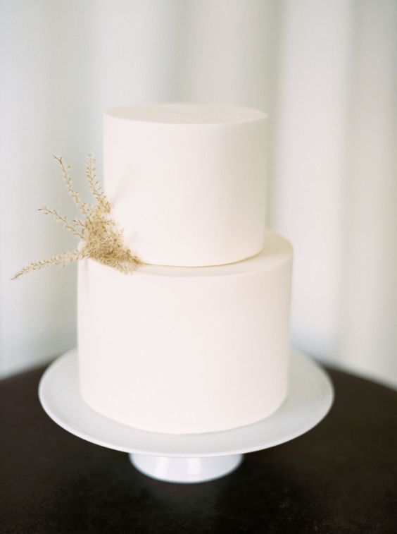 a pure white wedding cake decorated with just a couple of twigs of dried grass is a lovely idea for a minimalist wedding
