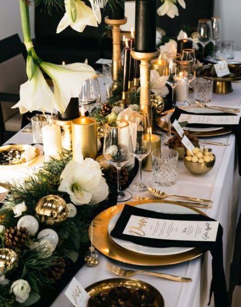 a refined and lush wedding tablescape with an evergreen and white blooms, pinecones, white ornaments, gold and white candles and gold chargers