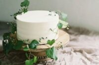 a simple and natural white wedding cake decorated with fresh greenery and berries for a delicate Nordic spring wedding