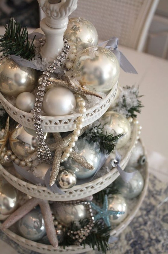a sparkling beach Christmas wedding centerpiece of a stand with silver and blue ornaments, glitter starfish and beads and sparkles