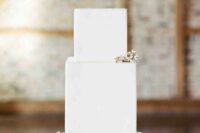 a square white wedding cake topped with a bit of berries is a clean and edgy idea for a winter minimalist wedding