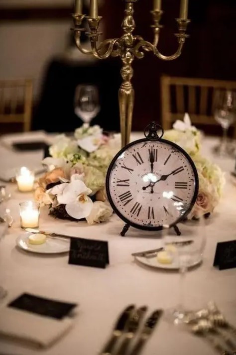 a stylish black and white tablescape with a lush neutral floral centerpiece, a gold candelabra and a clock