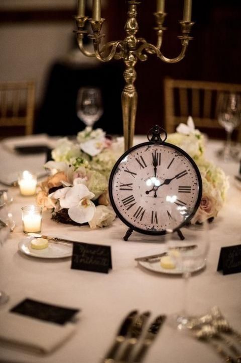 a stylish black and white tablescape with a lush neutral floral centerpiece, a gold candelabra and a clock