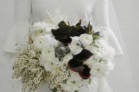 a stylish black and white wedding bouquet of white ranunculus, dark callas, white lily of the valley and greenery