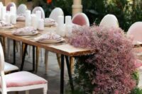 a stylish modern wedding reception table decorated with pink baby’s breath and greenery with no foam and pink napkins and pillar candles