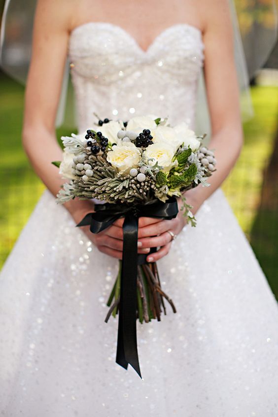 a stylish wedding bouquet of white roses, black and grey berries, greenery and a black ribbon bow is a lovely idea