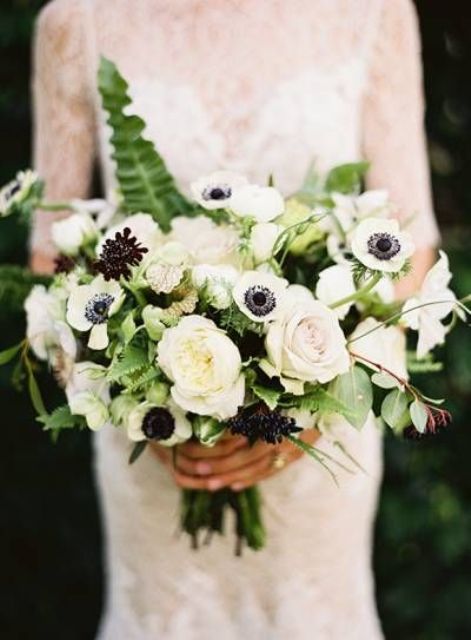a stylish wedding bouquet of white roses, peony roses and anemones, some black dahlias and berries and foliage