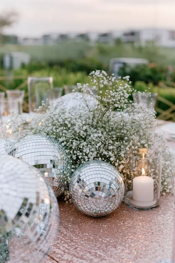 a super cool NYE wedding centerpiece of baby's breath and disco balls plus some candles promises a big party