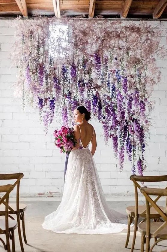 a unique wedding backdrop composed of blush blooms and purple and white delphinium is a lovely solution