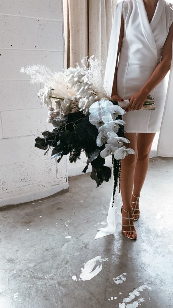 a unique wedding bouquet of white roses and orchids, black callas, dried grasses and twigs is a lovely idea for a modern bride