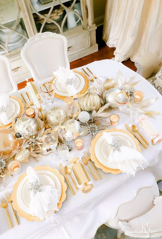 a wedding table runner done in silver and gold, with oversized ornaments and fake foliage plus candles