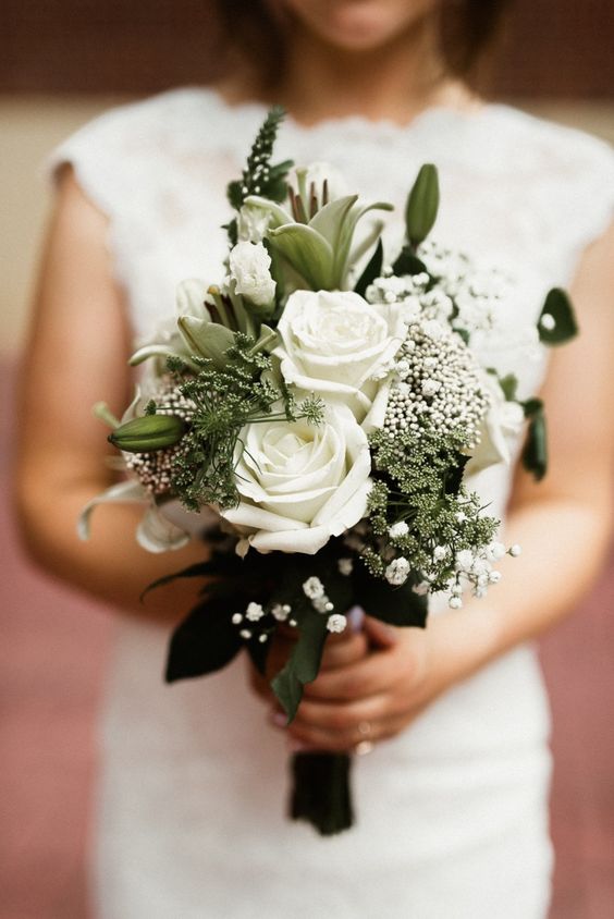 a white wedding bouquet of roses, baby's breath and lilies, greenery and a black ribbon bow is a stylish idea