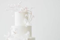 a white wedding cake decorated with white blooming branches is a lovely idea for a spring or summer minimalist wedding