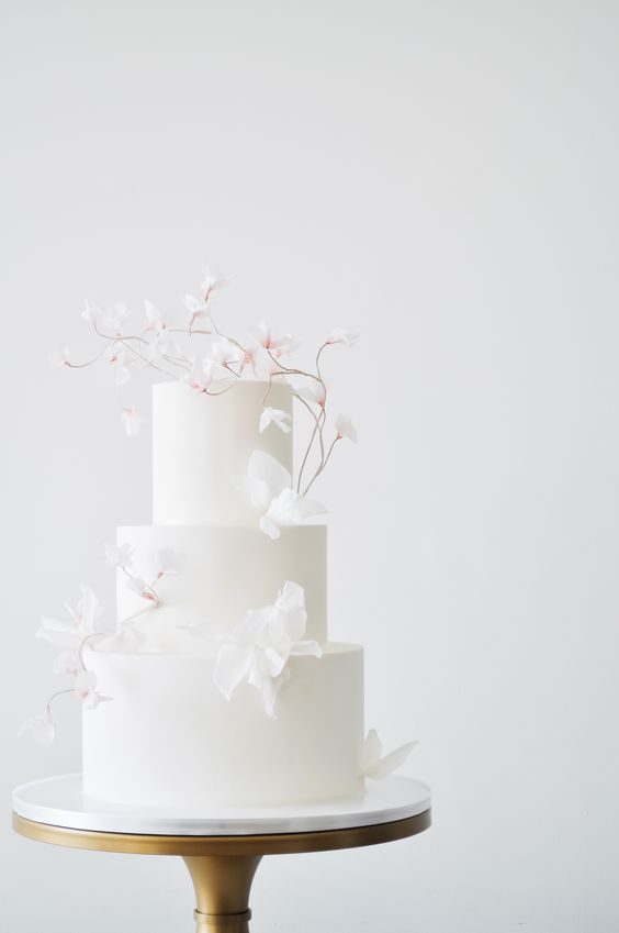 a white wedding cake decorated with white blooming branches is a lovely idea for a spring or summer minimalist wedding