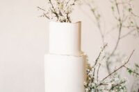 a white wedding cake with a raw edge and some blooming branches is a gorgeous idea for a minimalist spring wedding