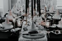 an awesome black and white NYE wedding tablescape with a silver sequin runner, black candles, white porcelain and silver napkins
