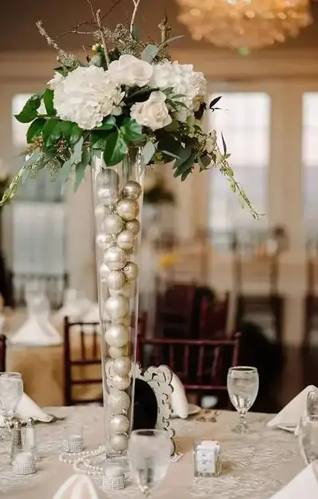 tall glass vases filled with ornaments and topped with flowers is a cool idea for a Christmas or NYE wedding