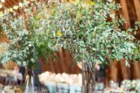 tall wedding centerpieces of greenery branches and some additional greenery on the table for a botanical feel