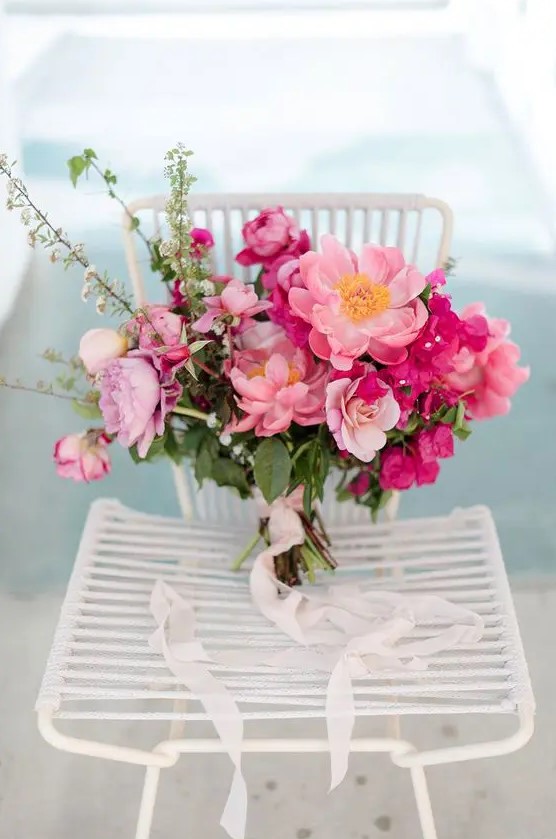 a beautiful pink wedding bouquet composed of pink peonies and fuchsia bougainvillea plus greenery