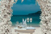 02 a breathtaking white wedding arch completely covered with blooms plus an ocean view are a bold combo for a ceremony