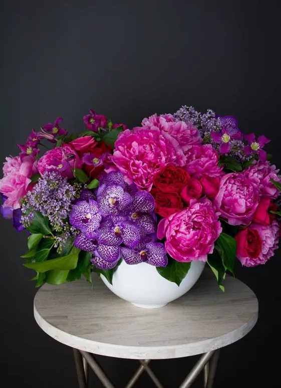 a fantastic jewel tone wedding centerpiece of deep red, hot pink and purple blooms and foliage is an amazing idea for the fall
