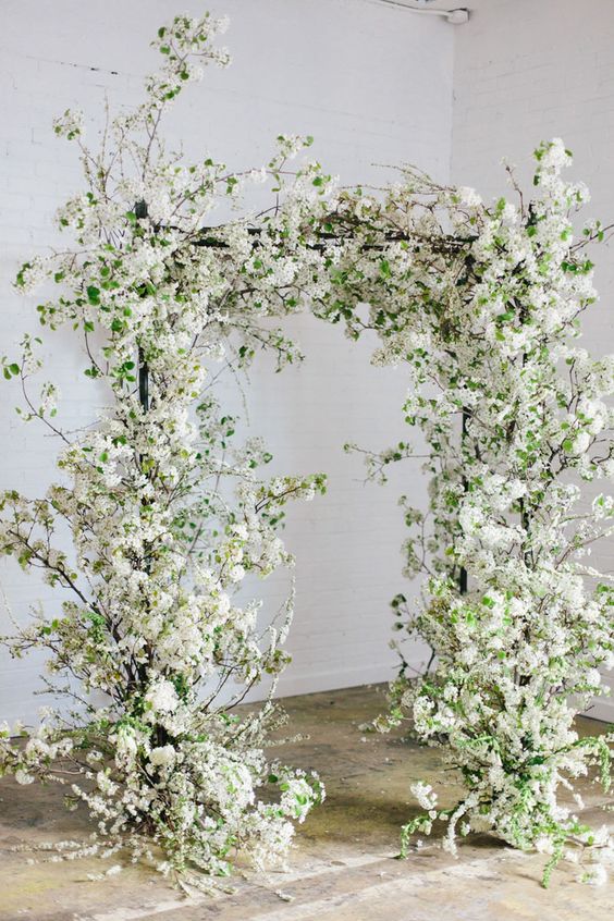 a fab blooming wedding arch covered with white blooming branches and some greenery is a lovely idea for spring or summer