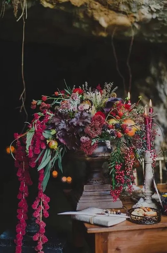 a luxurious wedding centerpiece with cascading blooms and foliage, colored fall leaves and berries