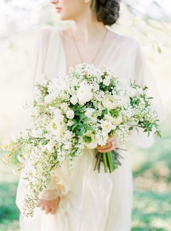 a dimensional white wedding bouquet with a cascading part and greenery for a chic and romantic look