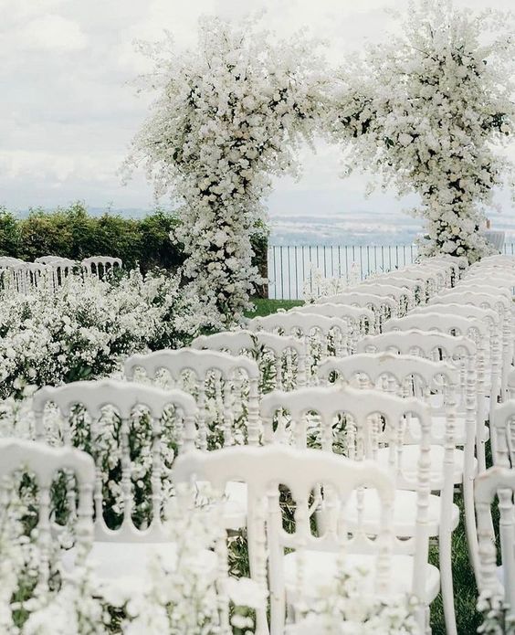 a gorgeous all white wedding arch covered with a lot of blooms and a matching wedding aisle will make your ceremony unforgettable