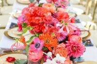 10 a vibrant wedding table setting with orange, red, hot pink blooms, blue and purple glasses, gold chargers and cutlery is wow