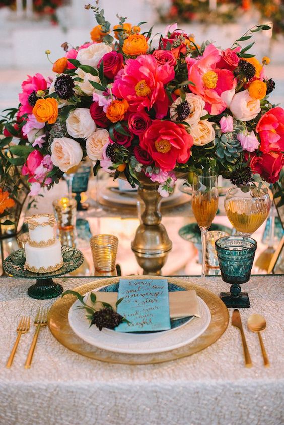 a super bold floral wedding centerpiece with peachy, pink, coral, orange, red and burgundy blooms and greenery is fantastic