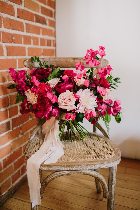 a lush fuchsia and blush wedding bouquet with plenty of dimension, greenery and blush ribbon is wow