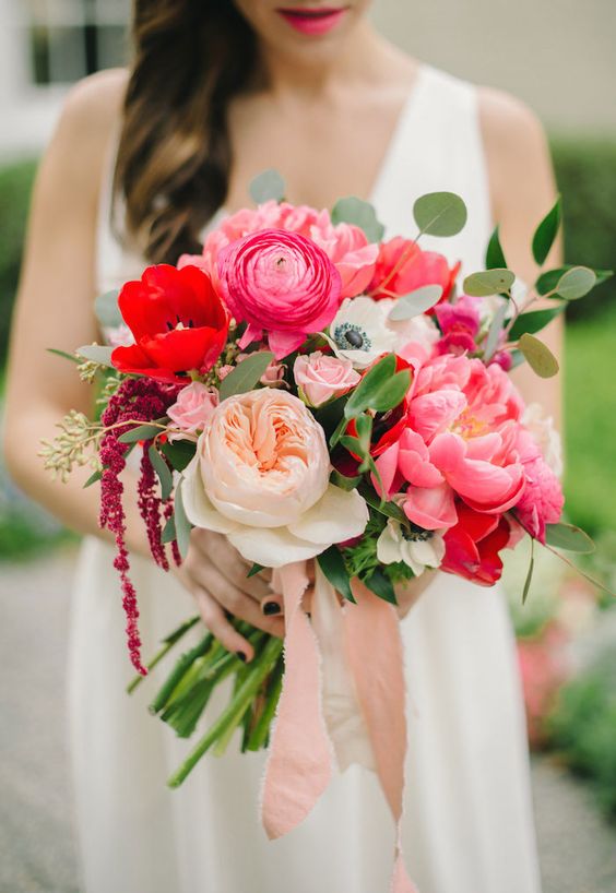a bold wedding bouquet of pink peonies and ranunculus, neutral peony roses and red anemones and some greenery