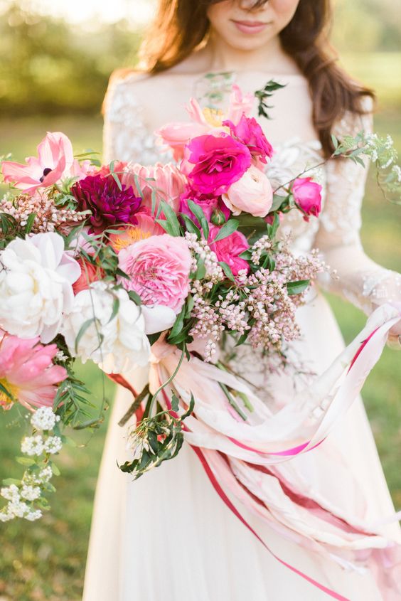a lush and dimensional pink wedding bouquet with white, light pink and hot pink blooms, berries and greenery plus ribbons