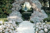 17 a lush wedding arch composed of baby’s breath and with an aisle covered with petals and neutral roses is wow
