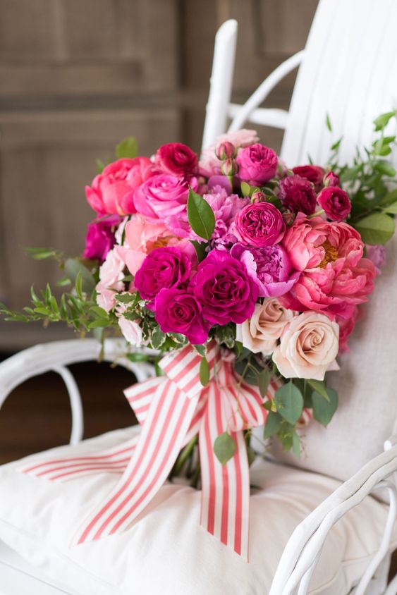 a bright wedding bouquet of pink, hot pink and fuchsia blooms, greenery and striped ribbons is a fantastic solution