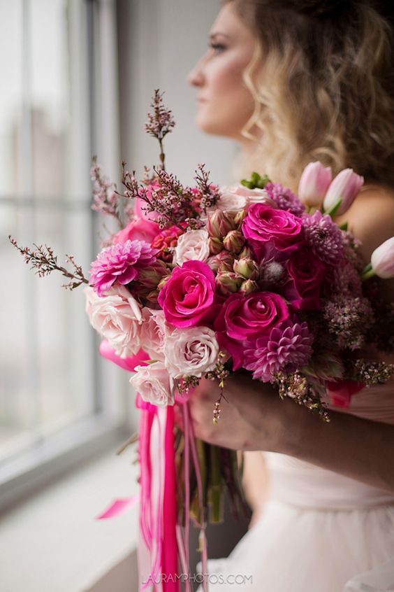 a pink wedding bouquet that includes blush, hot pink and fuchsia blooms and some waxflowers as fillers