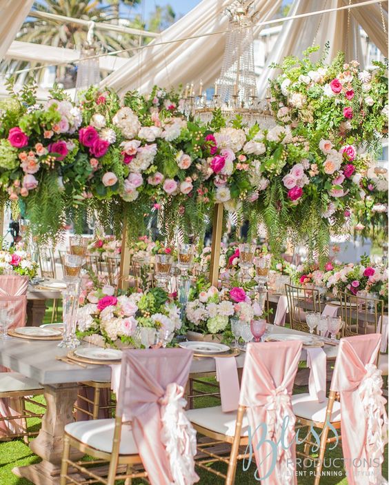 a beautiful flower-filled wedding reception with tall bold floral centerpieces and usual ones as a match looks amazing