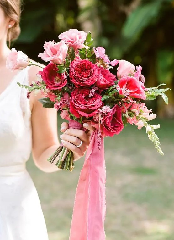 a vibrant wedding bouquet with pink and fuchsia and red blooms and berry hued ribbons is amazing for a bold wedding
