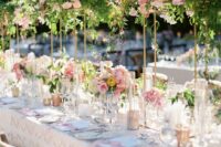 24 a chic wedding tablescape with pink floral centerpieces and matching tall centerpieces with much greenery and dark and pink blooms