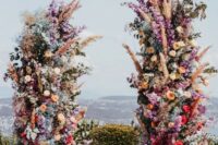 24 a super bold and colorful floral wedding altar of red, orange, purple, blue and pink blooms, pampas grass and greenery for a statement