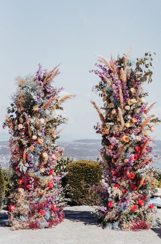 a super bold and colorful floral wedding altar of red, orange, purple, blue and pink blooms, pampas grass and greenery for a statement