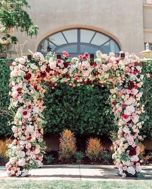 a bold and lush floral wedding arch with white, blush, light pink and burgundy blooms and greenery is amazing
