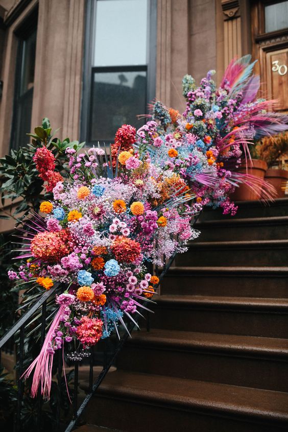 bright wedding banister decor with pink, orange, yellow and blue flowers plus pink fronds is jaw-dropping