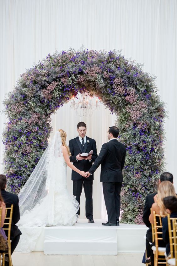a chic and lush wedding arch decorated with pale pink, pink and purple blooms is a gorgeous statement for a ceremony