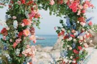 29 a colorful summer wedding arch with pink, red, coral, blue and white blooms and greenery is amazing for a bright wedding
