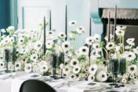 29 a lush and beautiful black and white wedding centerpiece of anemones, tall and thin black candles is a fresh take on classics